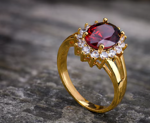 Elegant Gold-Tone Ring with Red Oval Gemstone & Halo Setting